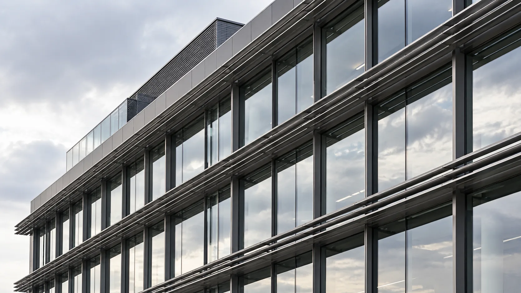 Façade tertiaire avec brise-soleil et ciel neutre.
